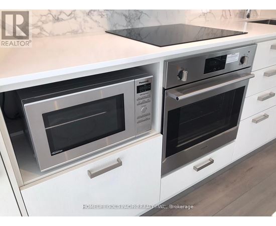 A modern kitchen with white cabinets and a marble backsplash.