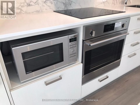 A modern kitchen with white cabinets and a marble backsplash.