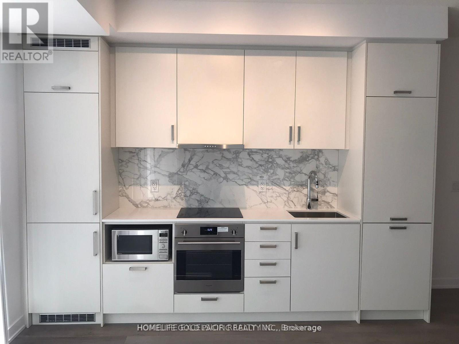 A kitchen with white cabinets and a marble backsplash.
