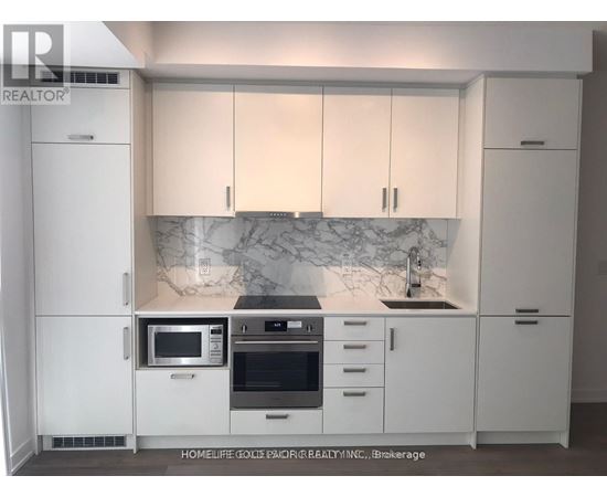 A kitchen with white cabinets and a marble backsplash.