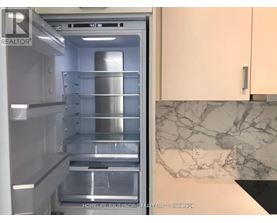 A refrigerator with the door open showing the empty shelves.