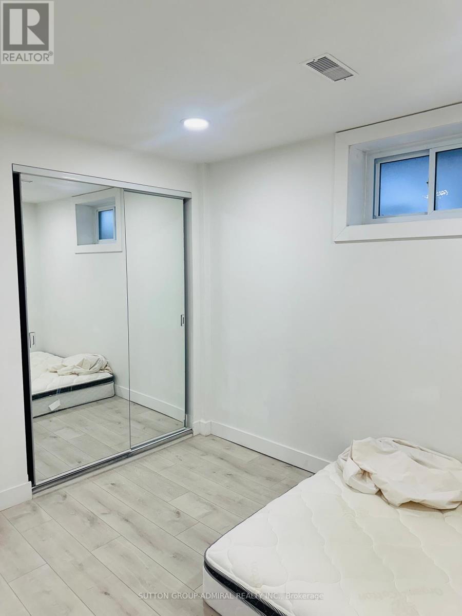 A bedroom with a bed, mirror, and a window.