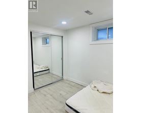 A bedroom with a bed, mirror, and a window.