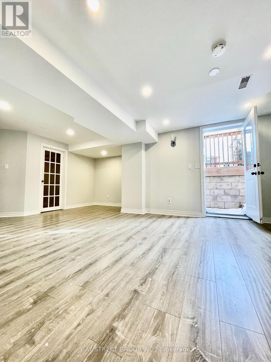 A spacious room with wooden flooring and white walls.
