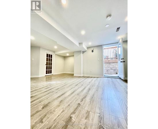 A spacious room with wooden flooring and white walls.