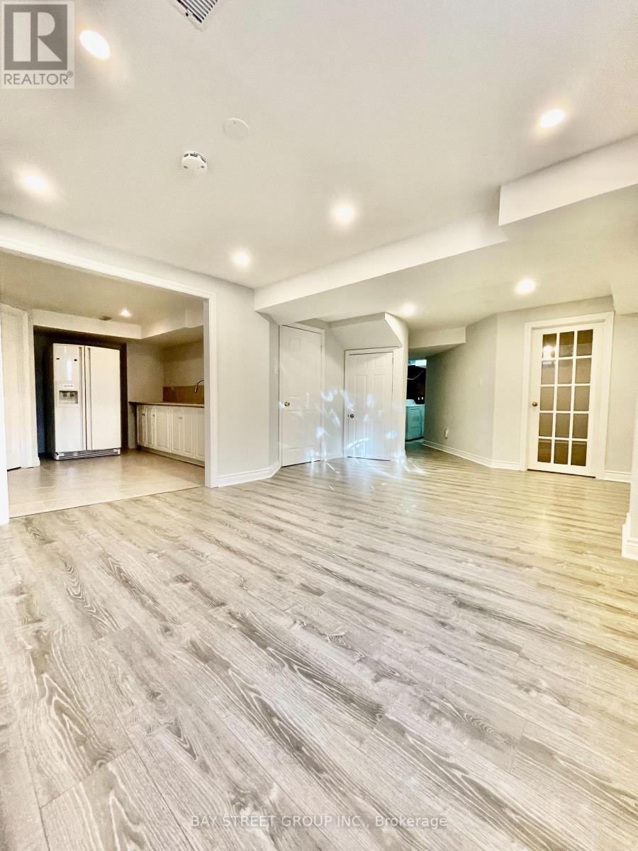 A spacious room with wooden flooring and white walls.