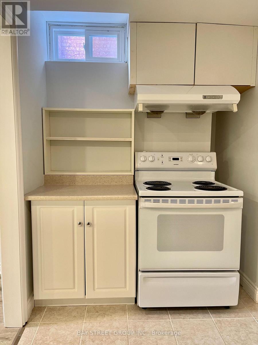 A white stove and oven in a kitchen with a window above it.
