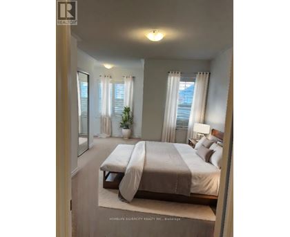 A bedroom with a large bed and a window with curtains.