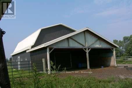 A large barn with a white roof and a fence in front of it.