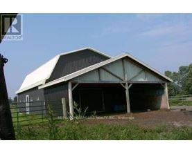 A large barn with a white roof and a fence in front of it.