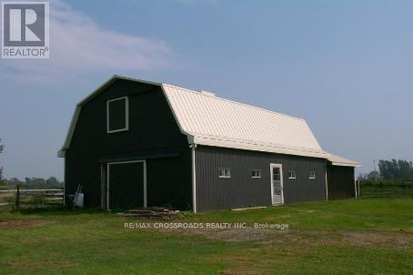 A barn with a white roof is situated in a grassy field.