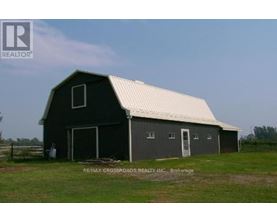 A barn with a white roof is situated in a grassy field.