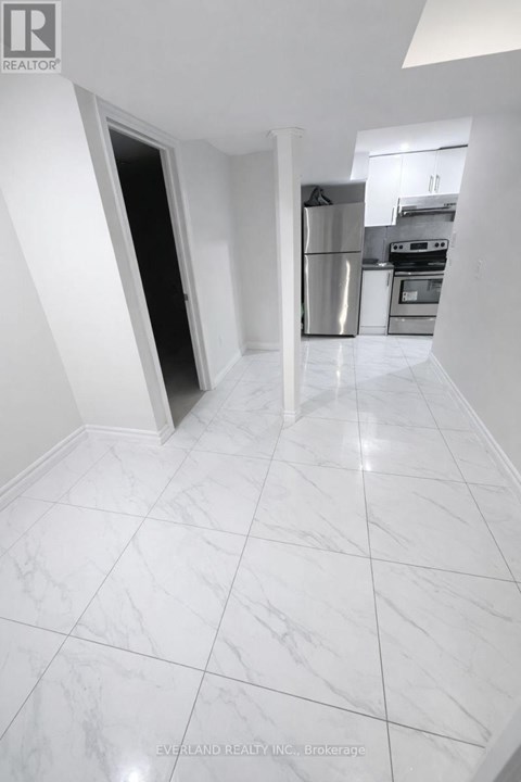A kitchen with white marble flooring and a stainless steel refrigerator.
