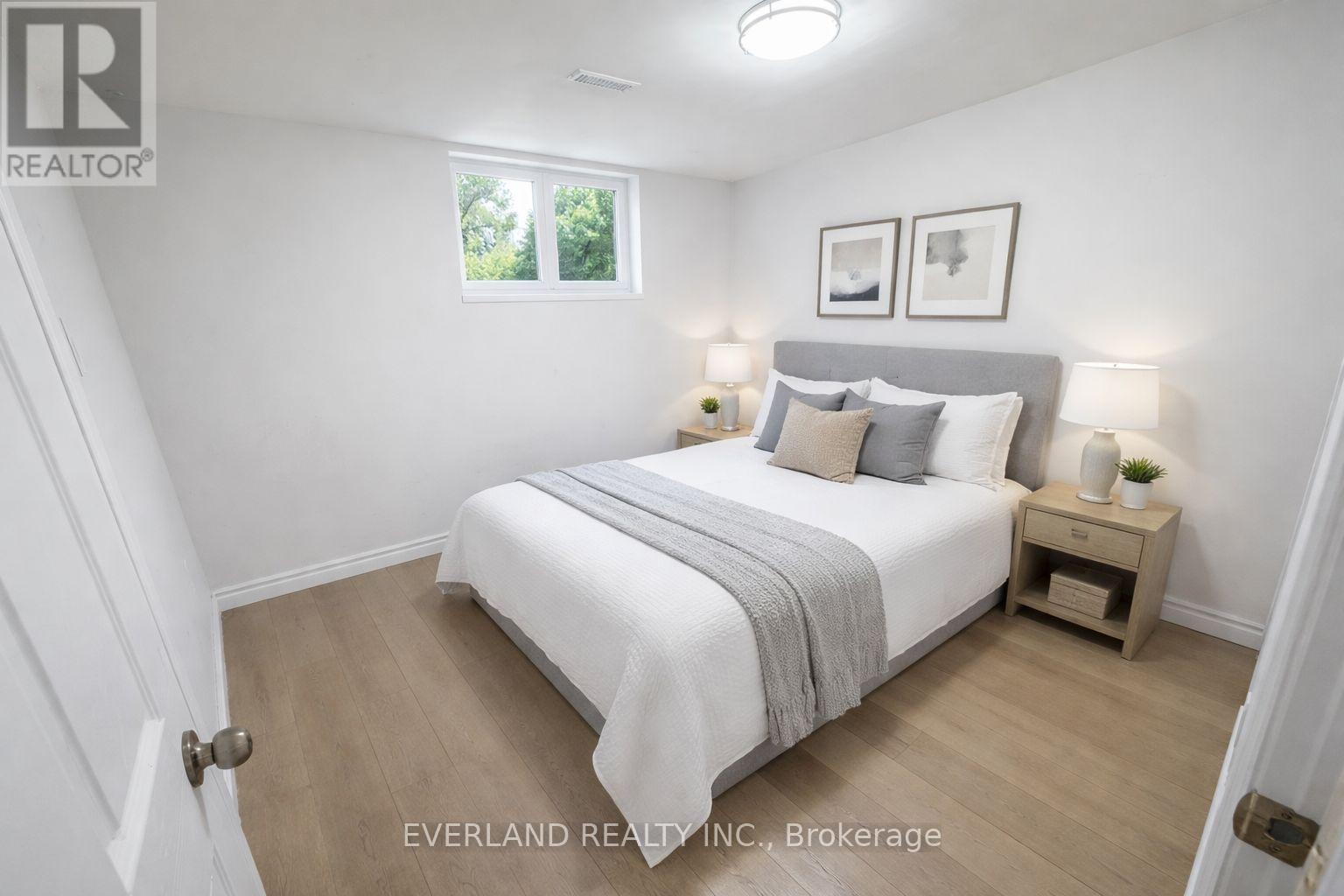A bedroom with a bed, nightstands, and a window.