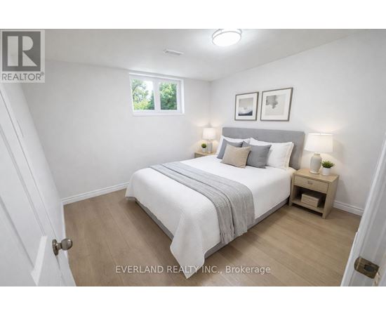 A bedroom with a bed, nightstands, and a window.