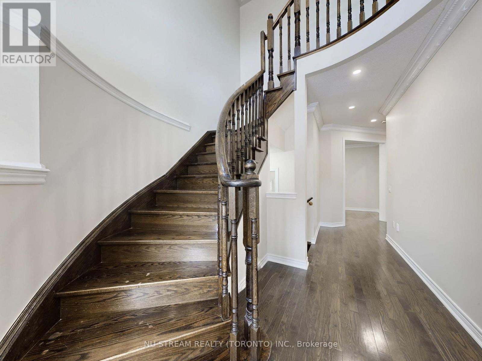 A wooden staircase with a metal railing leads to a door at the top.