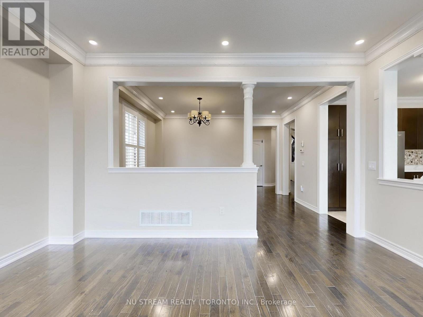 A spacious room with wooden floors and a chandelier.