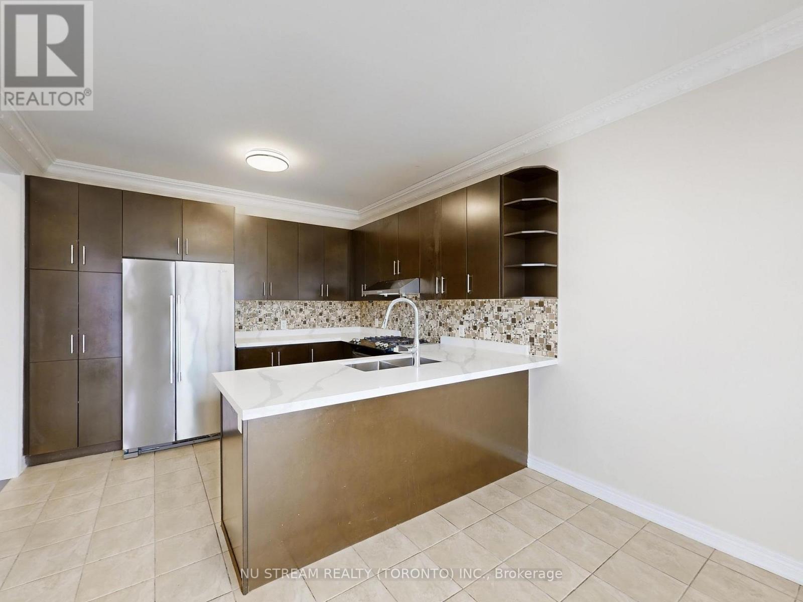 A modern kitchen with a stainless steel refrigerator and a marble backsplash.