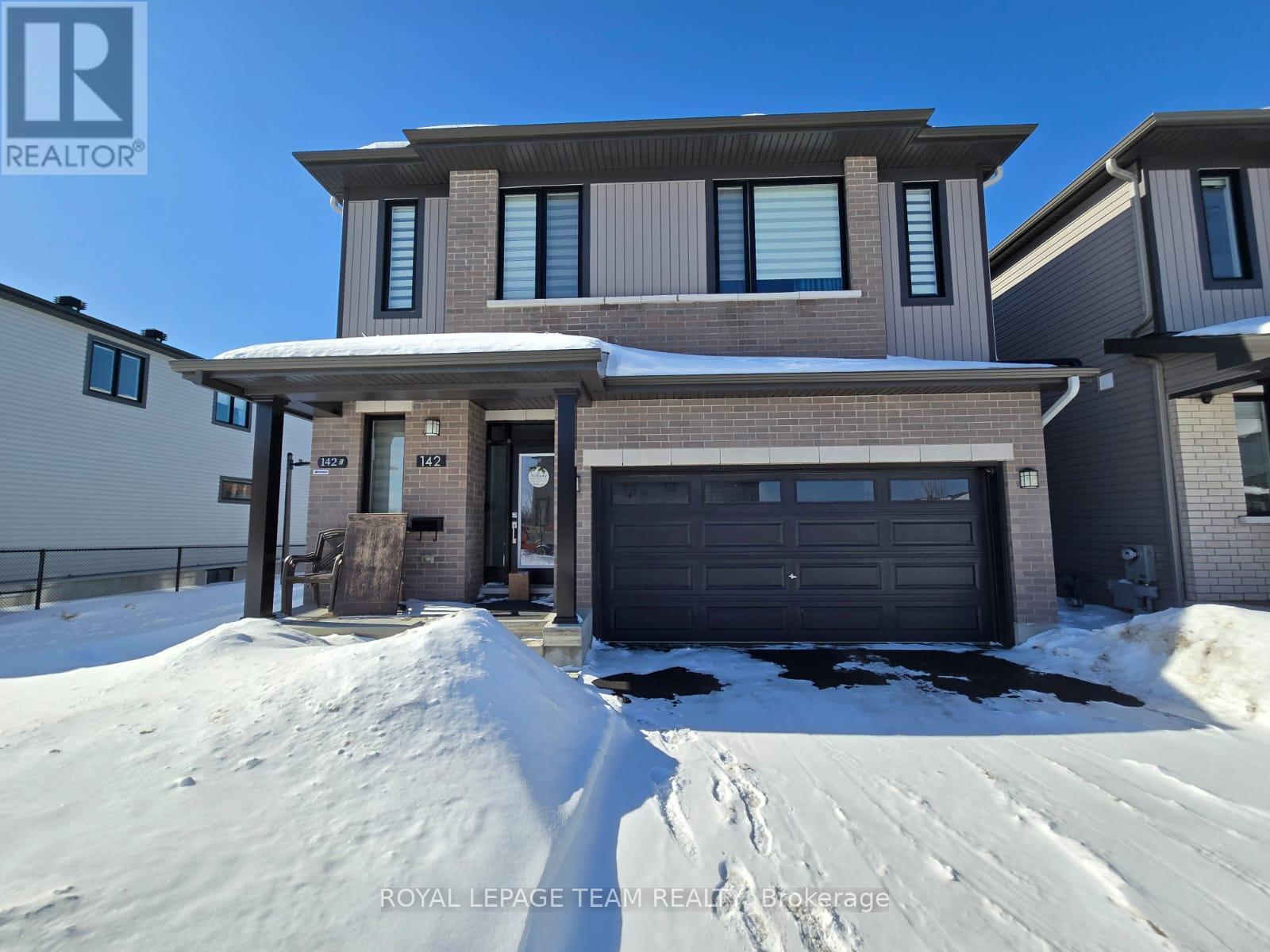 A house with a garage and a snow-covered ground in front of it.