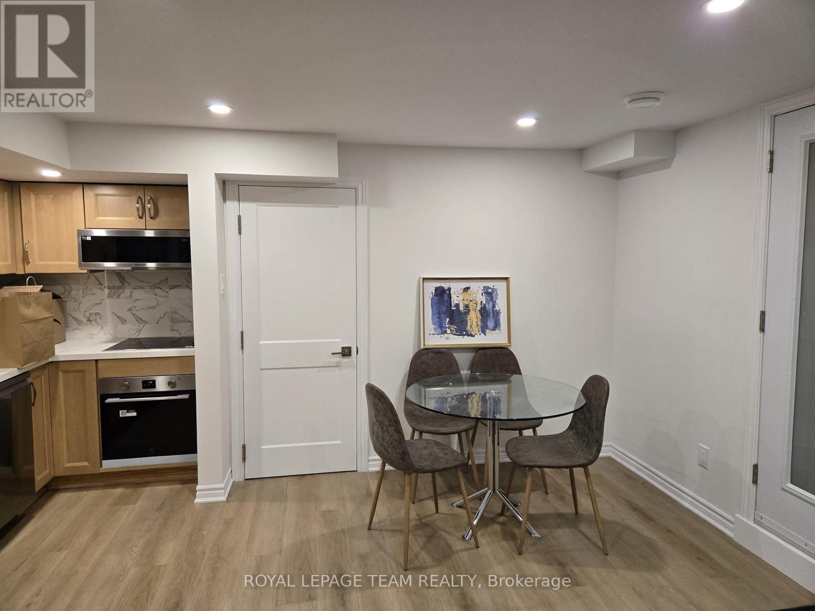 A spacious room with wooden flooring and white walls, with a pair of shoes on the floor.