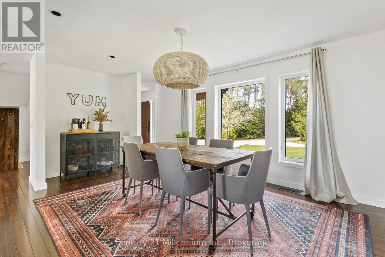 A dining room with a rug on the floor and a table with chairs.