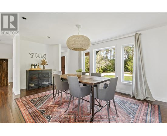 A dining room with a rug on the floor and a table with chairs.