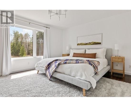A bedroom with a large bed and a view of trees outside the window.
