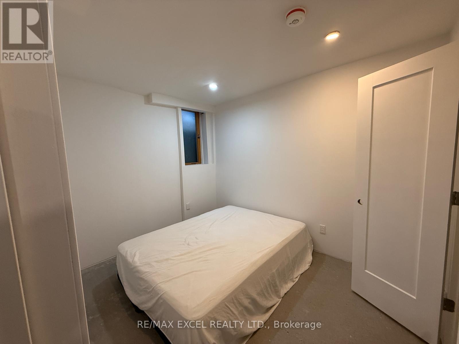A bedroom with a bed, a window, and a door.