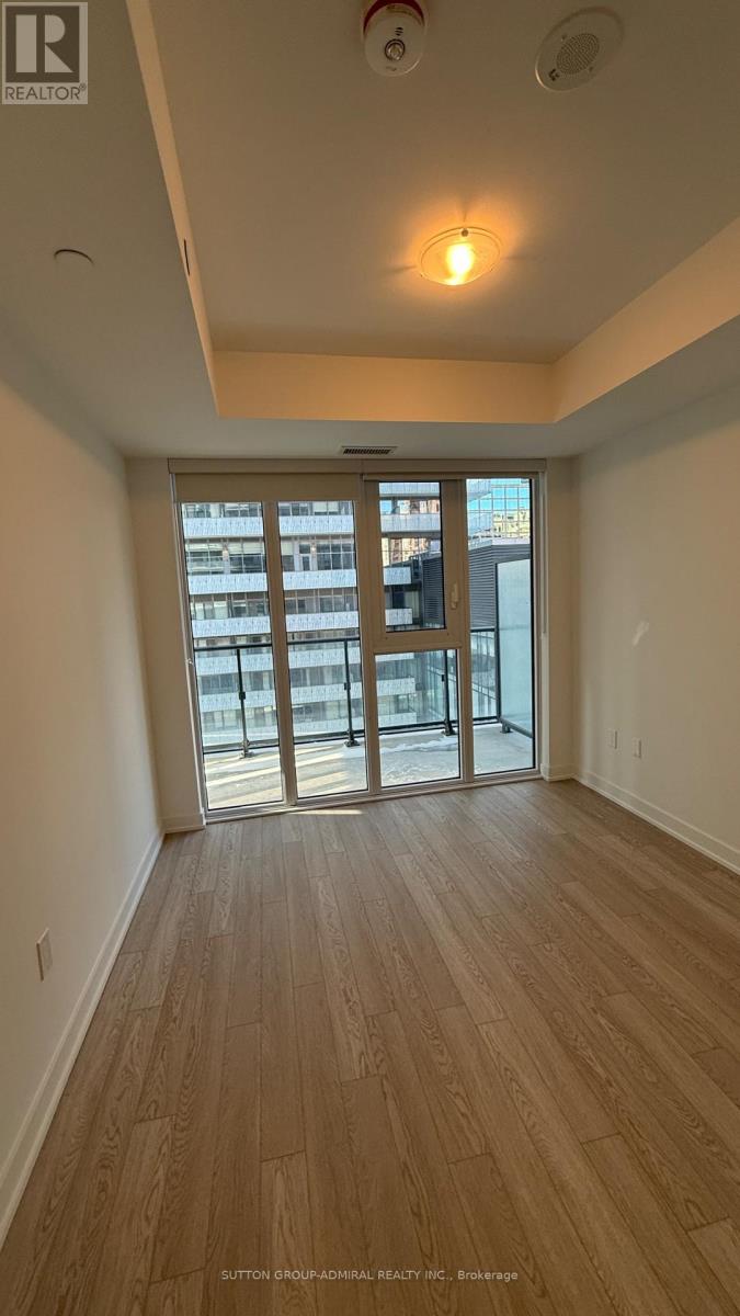 A room with wooden flooring and a sliding glass door leading to a balcony.