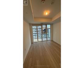 A room with wooden flooring and a sliding glass door leading to a balcony.