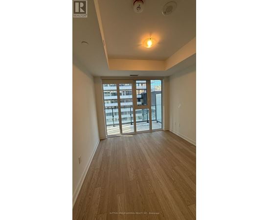 A room with wooden flooring and a sliding glass door leading to a balcony.