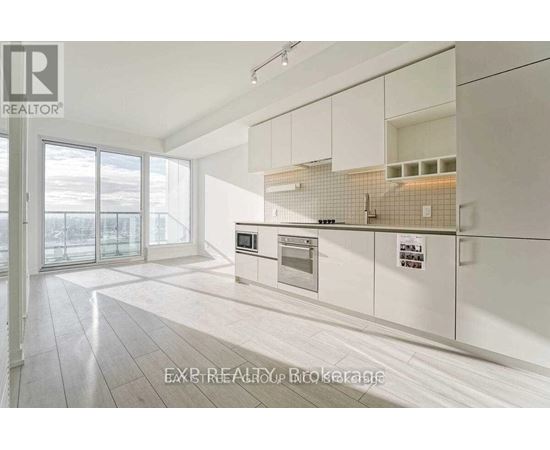 A modern kitchen with white cabinets and a tiled backsplash.