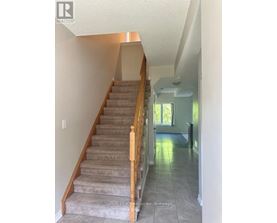 A staircase with a light brown carpet and wooden balusters.
