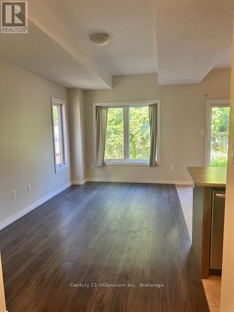 A room with wooden floors and white walls, with a window and a door visible.