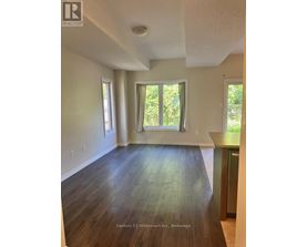 A room with wooden floors and white walls, with a window and a door visible.