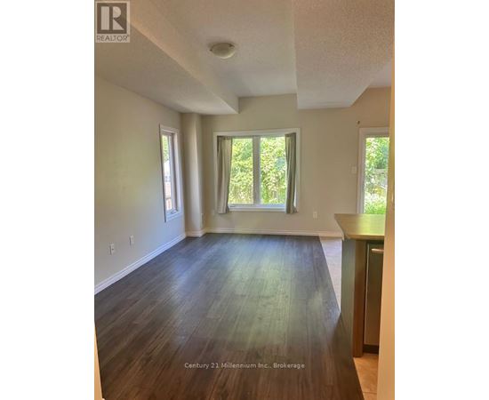 A room with wooden floors and white walls, with a window and a door visible.