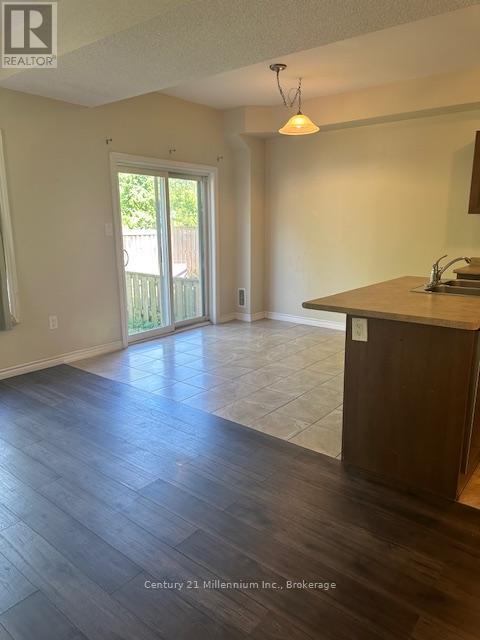 A realtor photo of an empty room with wood floors and a large window.
