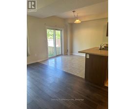 A realtor photo of an empty room with wood floors and a large window.