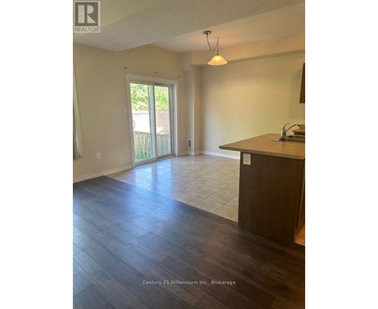 A realtor photo of an empty room with wood floors and a large window.