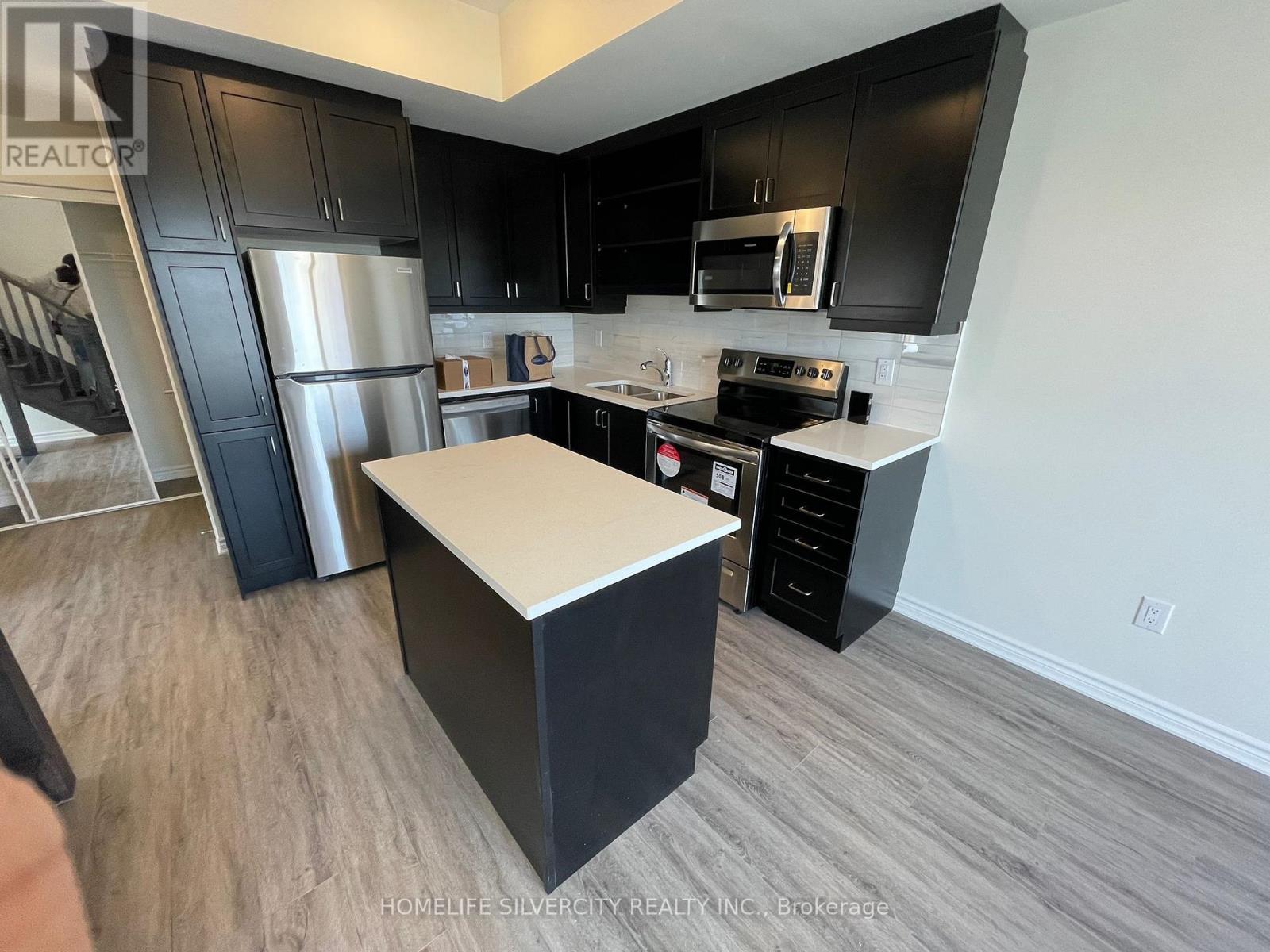 A kitchen with black cabinets and a white island.