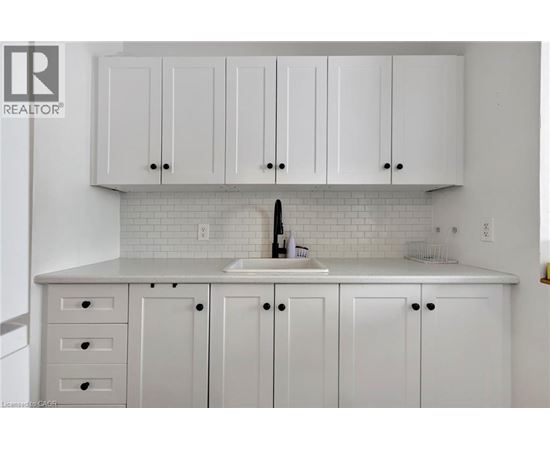 A kitchen with white cabinets and a white sink.
