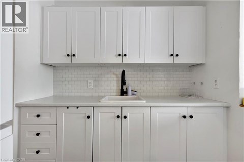 A kitchen with white cabinets and a white sink.