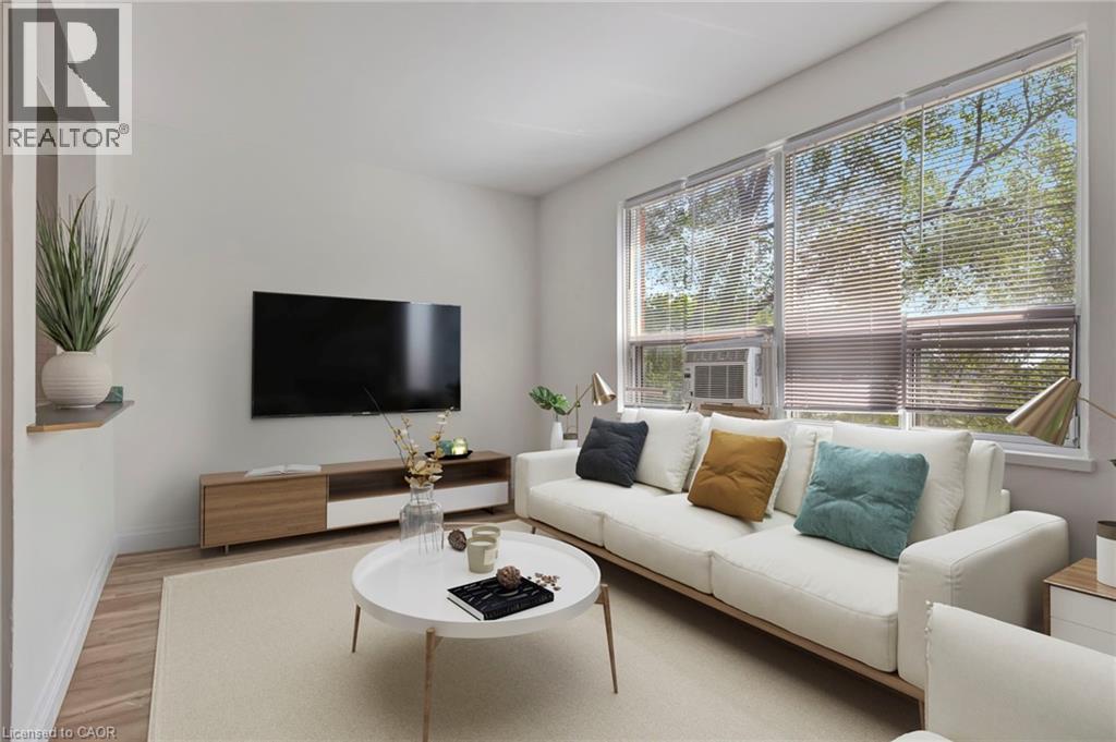 A living room with a white couch, a coffee table, and a flat screen TV mounted on the wall.