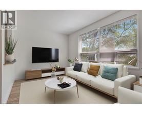 A living room with a white couch, a coffee table, and a flat screen TV mounted on the wall.