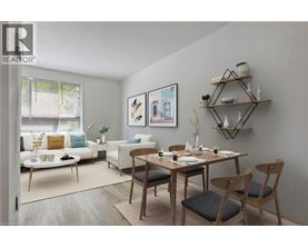 A dining room with a table set for two and a couch with a pillow in the background.