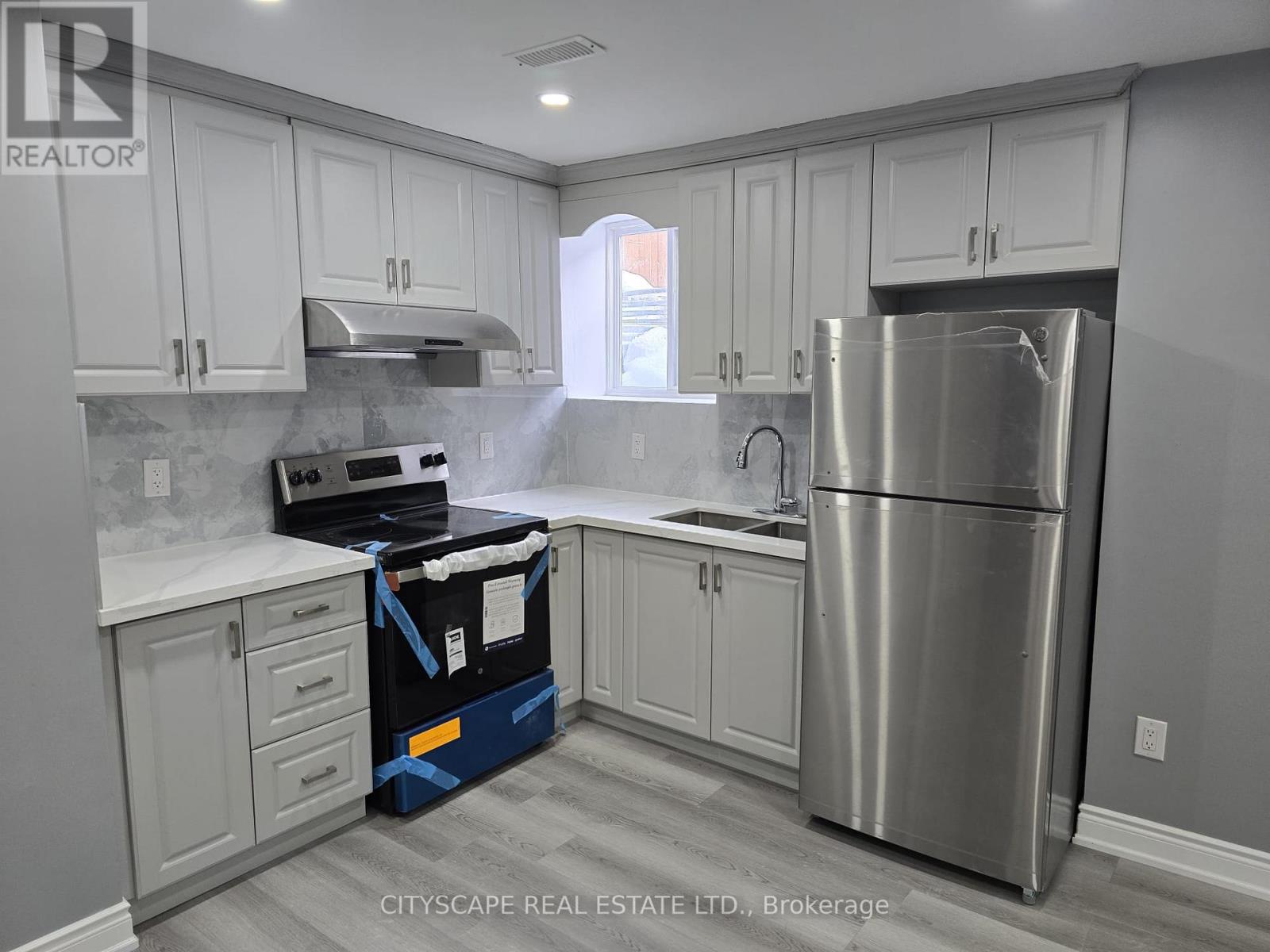 A kitchen with a stainless steel refrigerator and a black and blue box on the floor.