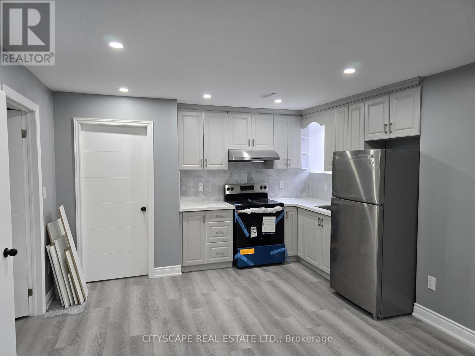 A kitchen with a refrigerator, stove, and cabinets is on the market.