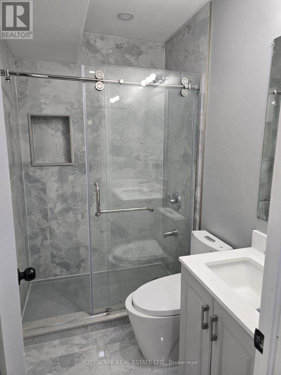A bathroom with a glass shower stall and a toilet.