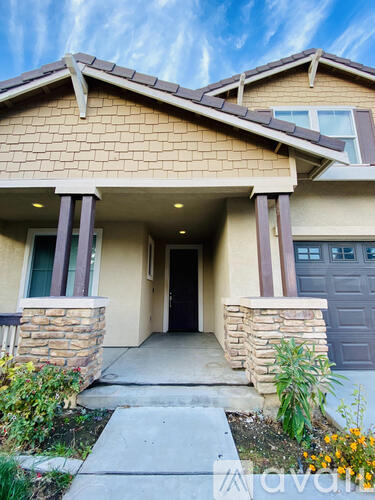 A house with a brown roof and a stone pillar in front of the entrance.