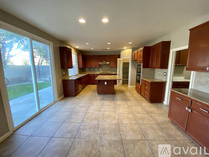 A spacious kitchen with brown cabinets and a tiled floor.